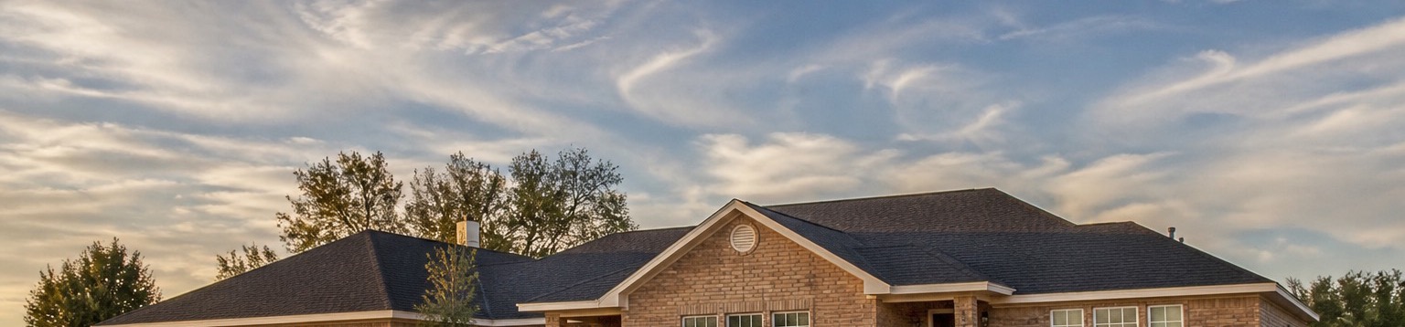 A single-story Texas brick home under an open sky, wide windows across the front elevation